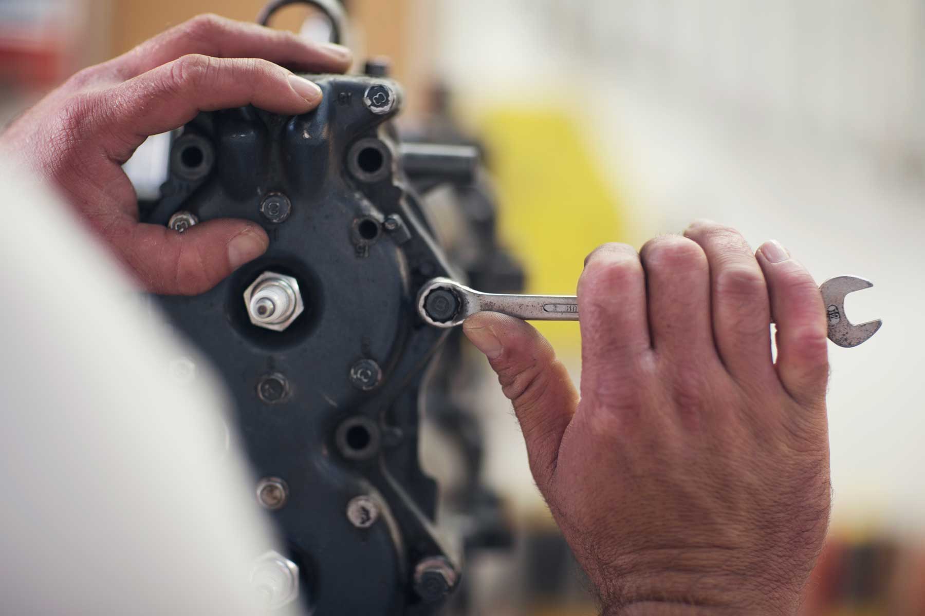 close up of male hands repairing outboard motor