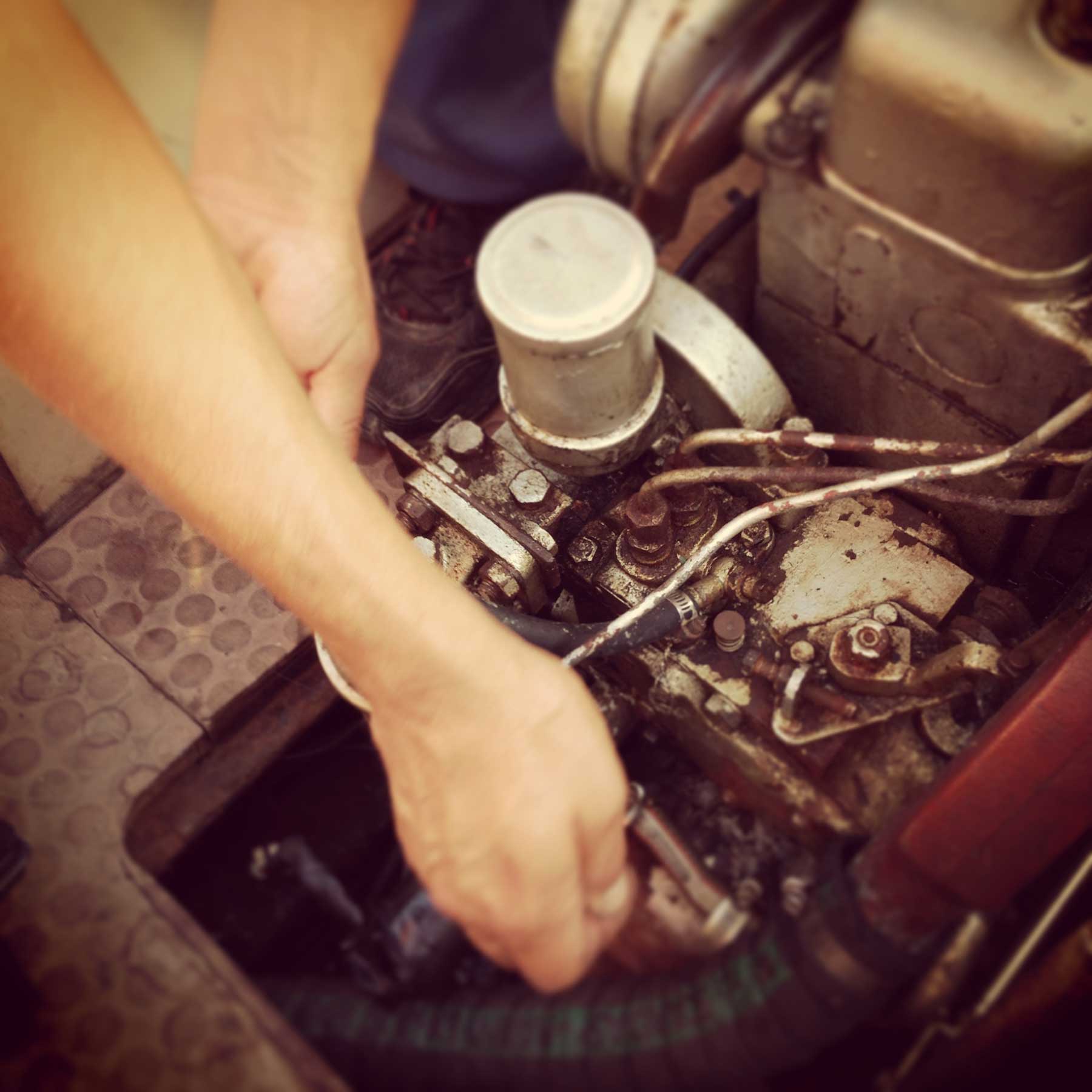 man repairing old rusty diesel boat engine